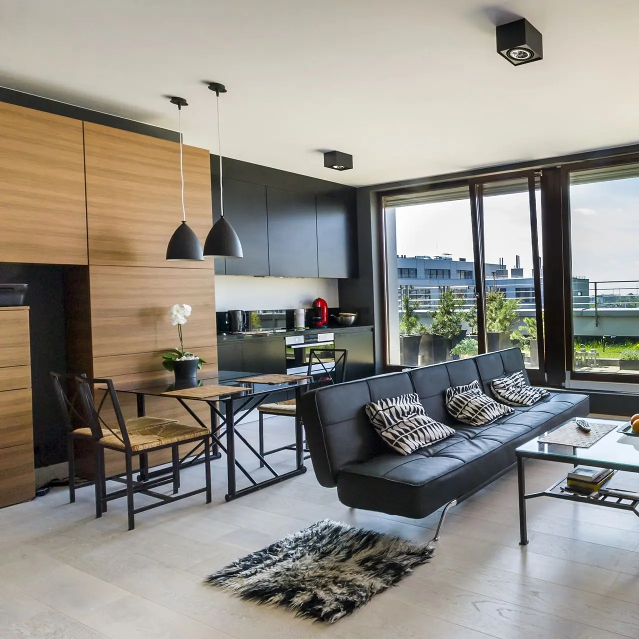 Modern living room with wood paneling, black leather sofa, and dining area