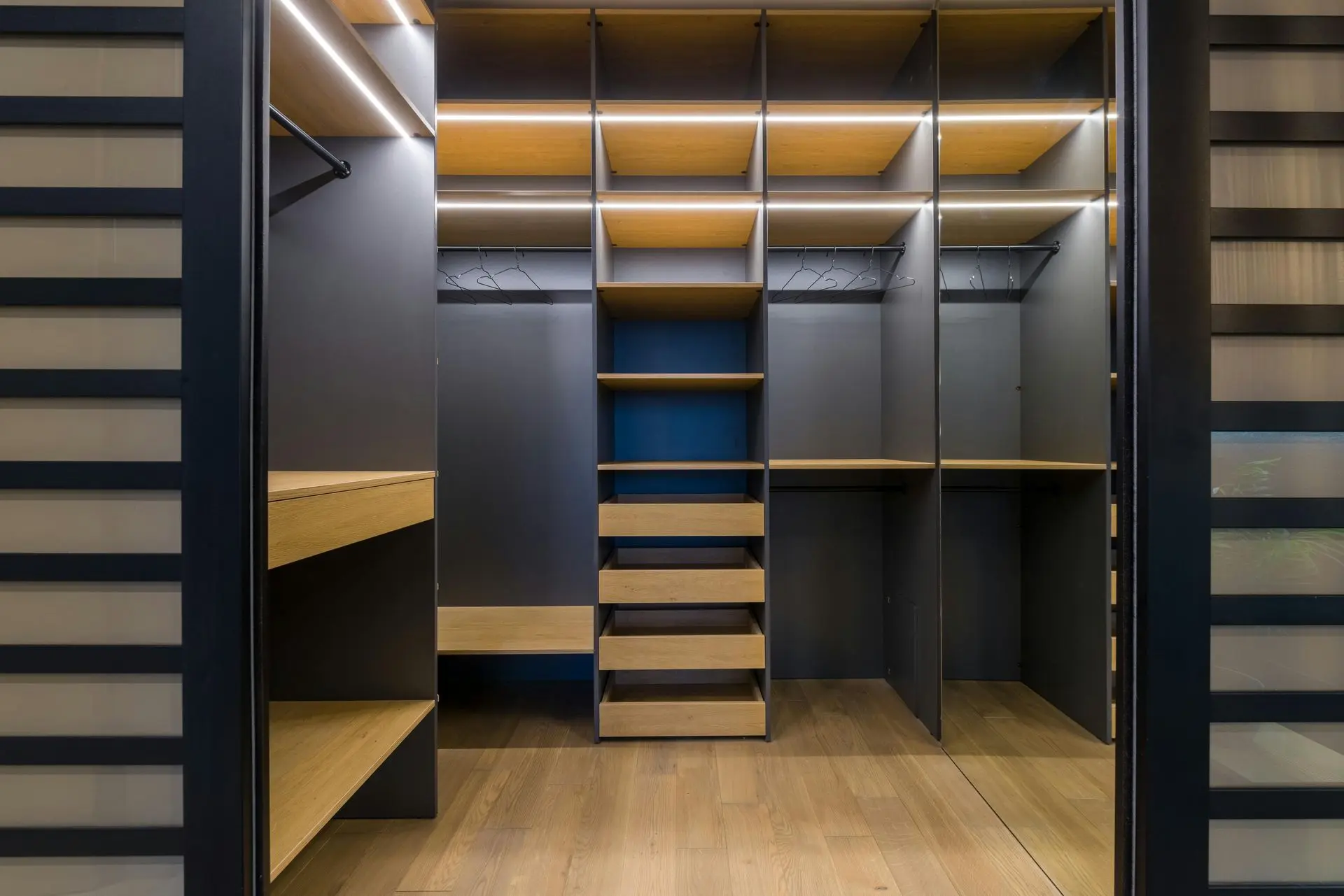 Modern walk-in closet with custom shelving, drawers, hanging rails, and integrated lighting