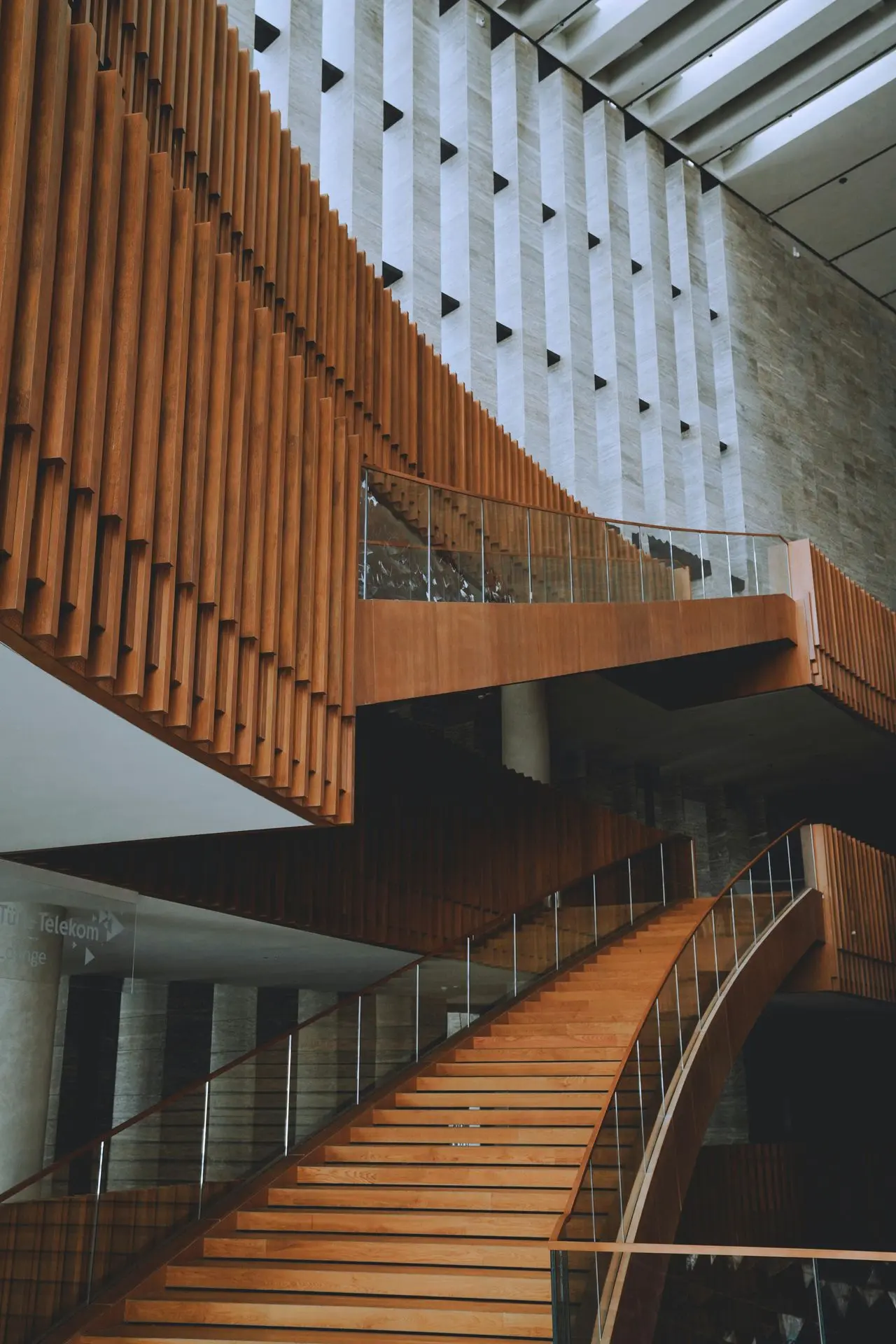 Modern wood staircase with glass balustrade and vertical slat wall showcasing architectural millwork