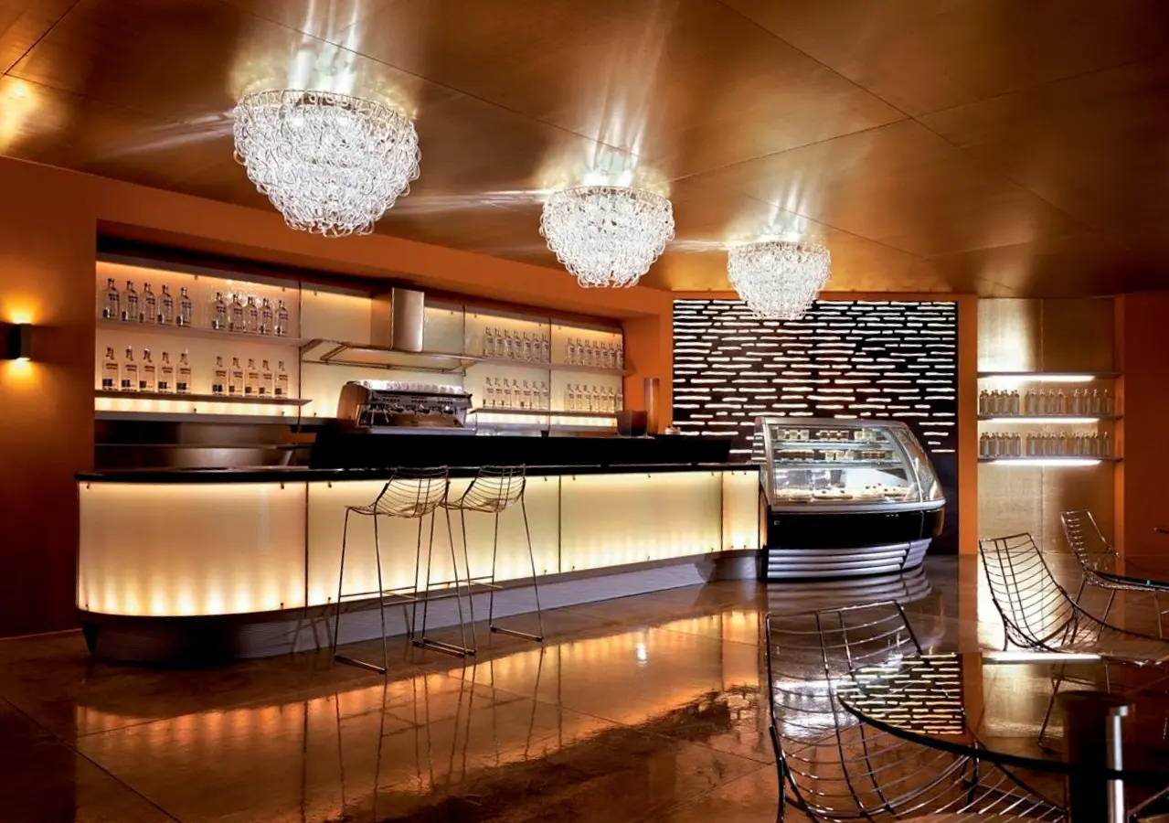 Hospitality architectural millwork bar with illuminated counter, back bar shelving, and chandelier lighting