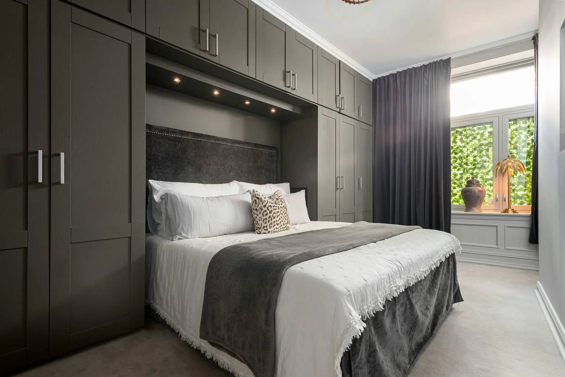Luxury custom cabinetry in a modern bedroom with built-in wardrobes, overhead storage, and integrated bed design