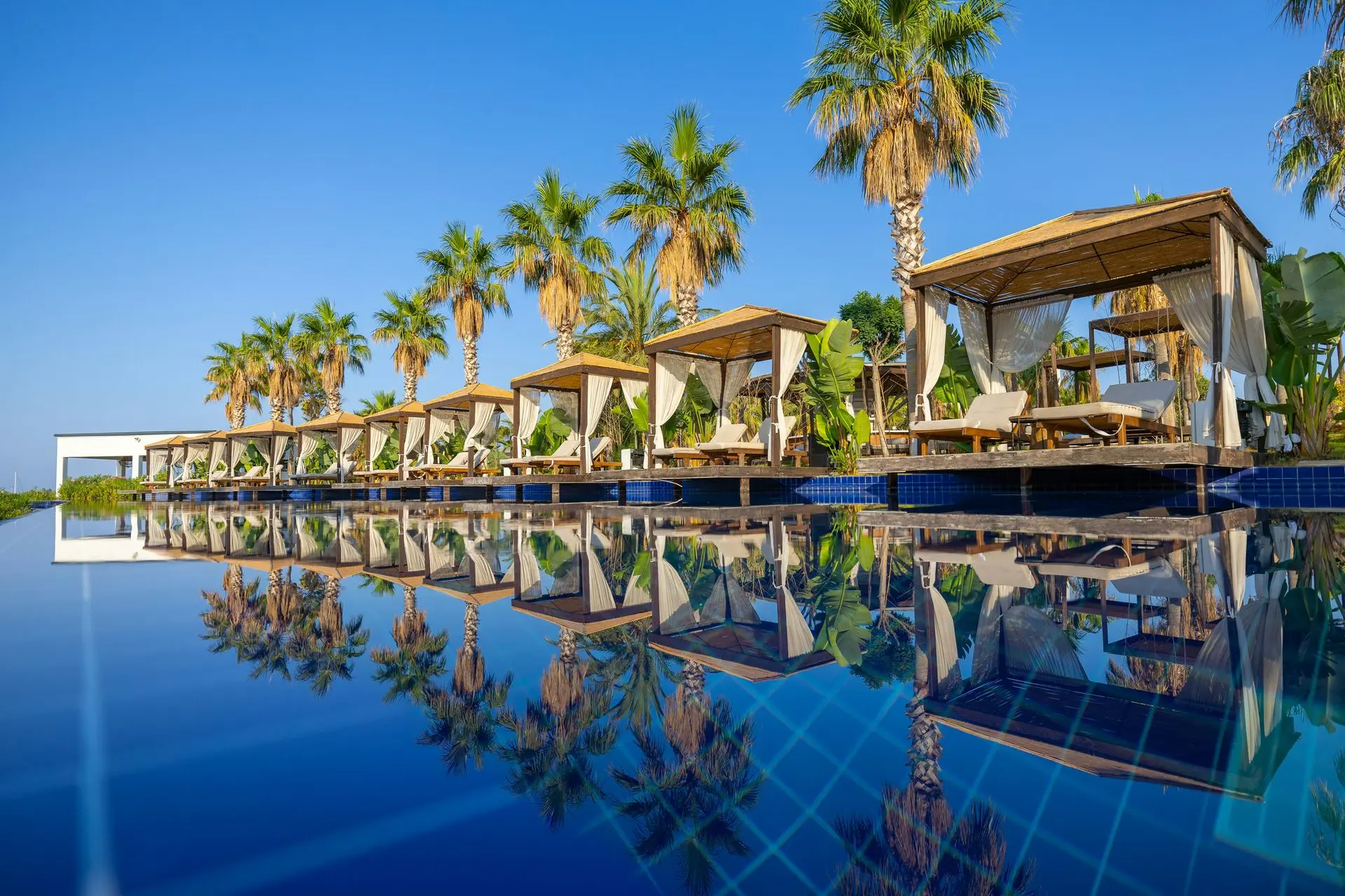 Luxury hotel outdoor furniture with poolside loungers, cabanas and sunbeds in resort setting