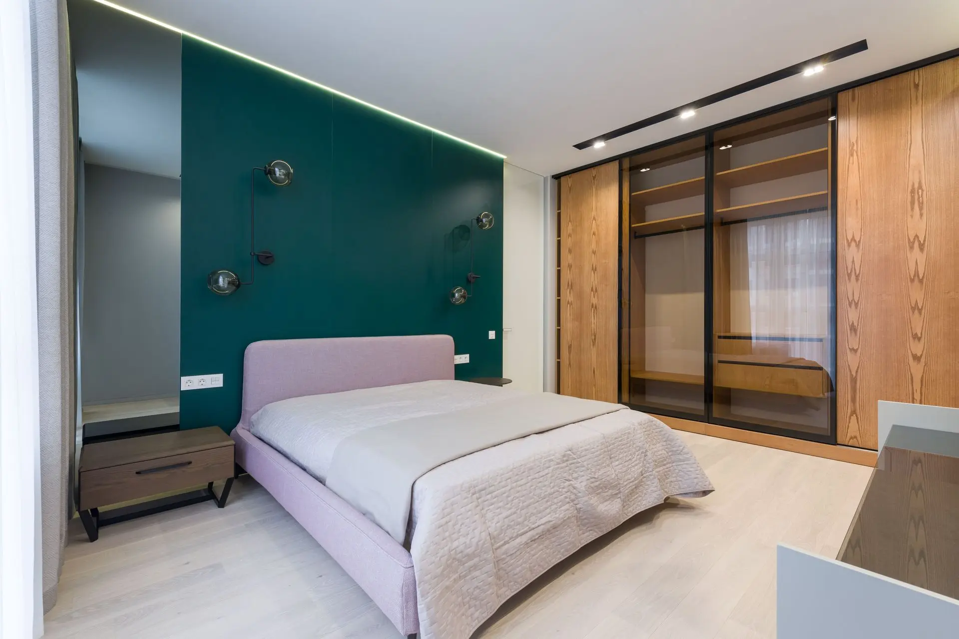 Hotel wardrobe with glass doors and integrated lighting in a modern guest room