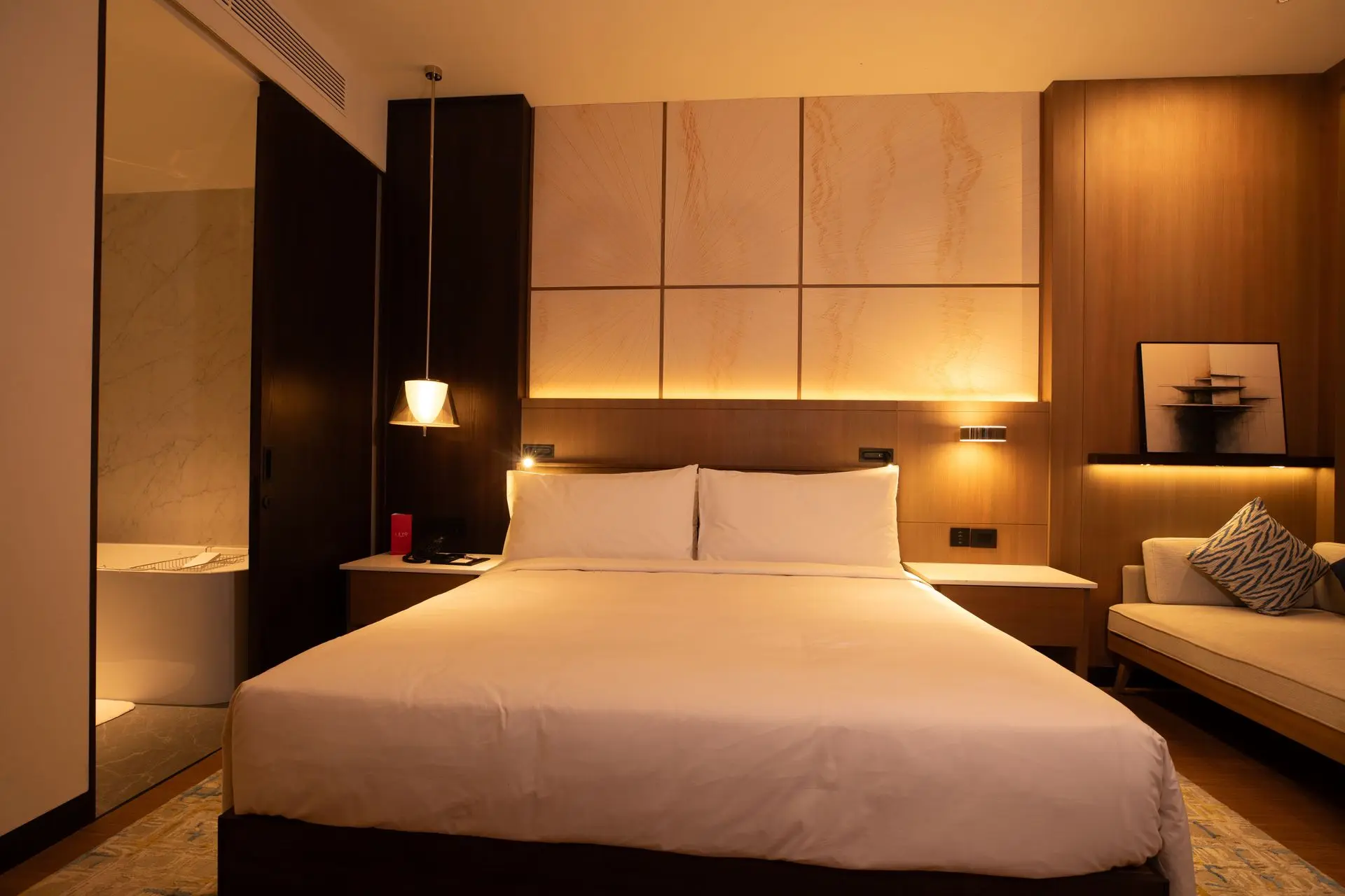 Custom Hotel Millwork for Large-Scale Hospitality Projects Hotel guestroom featuring custom wood wall panels, a built-in headboard, and integrated bedside tables