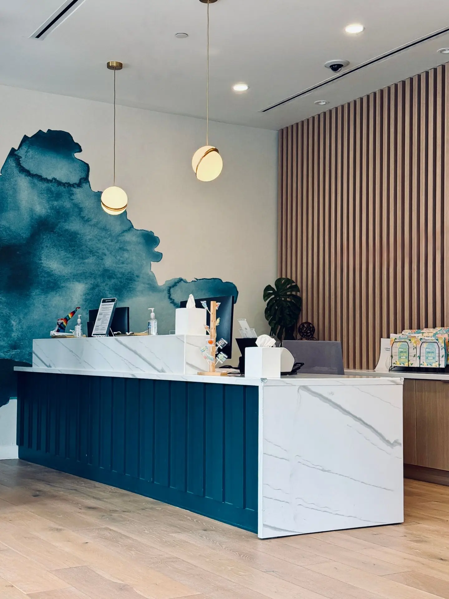 Custom Architectural Millwork for Commercial Reception Areas Custom reception desk with fluted blue panels, a white countertop, and wood-slat wall detailing