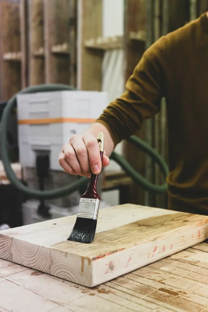 Craftsperson applying a wood finish by hand with a brush